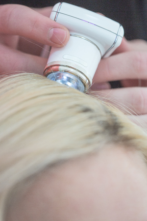 photo of hair treatment. hair testing. man's hand with the device for testing fiber optic links in red backgroundの写真素材