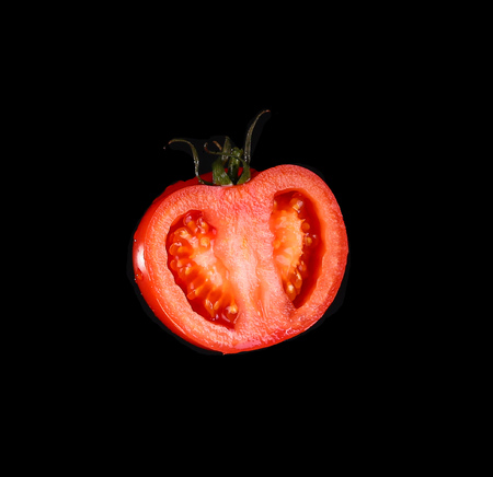 The red tomato cut half-and-half on a black background. Kind with a side.の写真素材