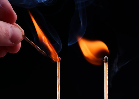 Ignition of a match, with smoke on dark background. Hand holding burning match stickの写真素材