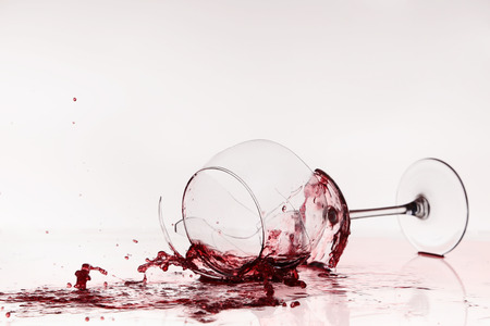 Broken wineglass on the table. Poured red wine, like blood.の写真素材