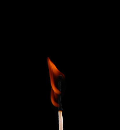 Ignition of a match, with smoke on dark background. Hand holding burning match stickの写真素材