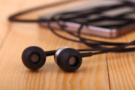 mobile phone with pair of earphone on wooden tableの写真素材
