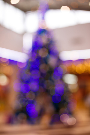 Giant Christmas tree in shopping mall. Blurred background. Christmas tree with gold decoration in shopping mall.Christmas clearance sales at the shopping mall. Elegant Christmas tree in a shopping mallの写真素材