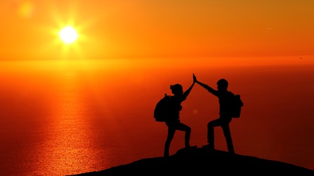 Male and female hikers climbing up mountain cliff and one of them giving helping hand. People helping and, team work concept.の写真素材