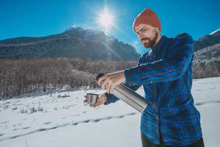 Man holding a flask in on a snowy mountainの写真素材
