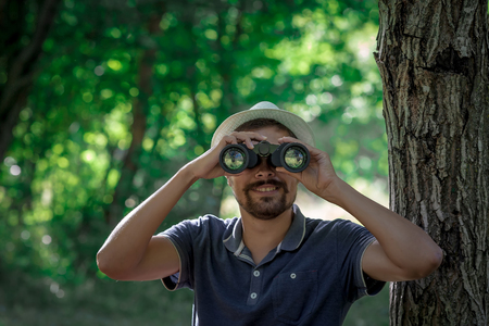 Male hiker looking through binoculars in forestの写真素材
