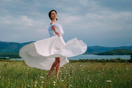 Beautiful woman enjoying daisy field, nice female lying down in meadow of flowers, pretty girl relaxing outdoor, having fun, holding plant, happy young lady and spring green nature, harmony conceptの写真素材