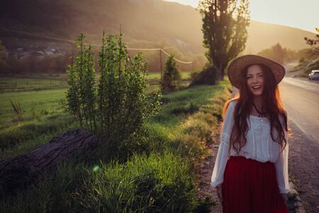 happy laughing girl holding straw walking in the green summer parkの写真素材