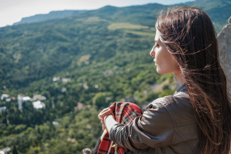 Young woman sitting on cliff and enjoy the view. A girl in a kilt, a Scandinavian mood. Crimea,...