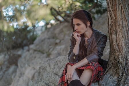 Young woman sitting on cliff and enjoy the view. A girl in a kilt, a Scandinavian mood. Crimea, Mount Catの写真素材