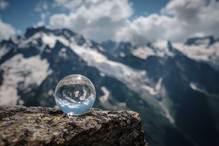 Transparent glass sphere and snow-capped peaks in the background. Concept and idea of travelの写真素材