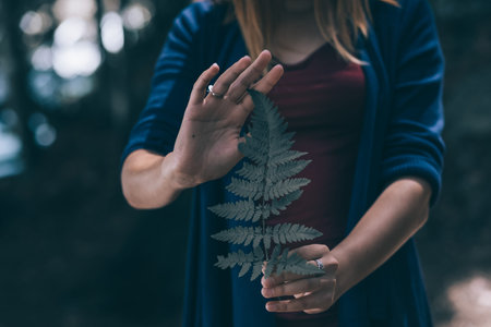 happy young woman, with fern leaf in hands in the forest