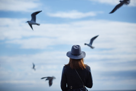 Girl looking at the calm sea on the with wind in her hair and seagulls on the background. Autumn in the Hatの写真素材
