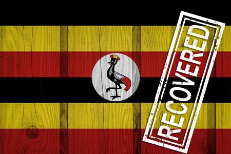 flag of Uganda that survived or recovered from the infections of corona virus epidemic or coronavirus. Grunge flag with stamp Recoveredの写真素材