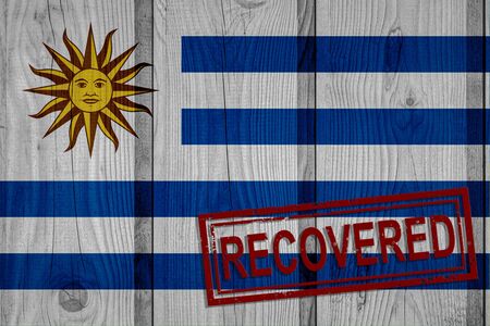 flag of Uruguay that survived or recovered from the infections of corona virus epidemic or coronavirus. Grunge flag with stamp Recoveredの写真素材
