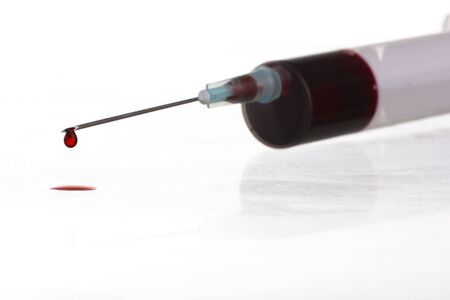 Macro view of drop of blood from syringe over white background. Blood chemistry. Blood test for viruses.の写真素材