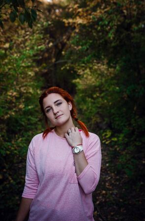 Beautiful young red-haired woman in the autumn forest. idea and concept of free time, happiness, care and freedom, outdoor activities and a healthy lifestyleの写真素材