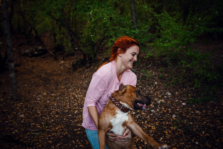 redhaired woman with her dog have fun on the walking. idea and concept of free time, happiness, care...