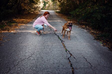 redhaired woman with her dog have fun on the walking. idea and concept of free time, happiness, care and freedom, long walks in the forestの写真素材