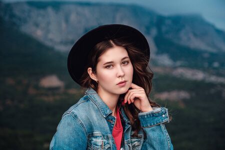 happy asian traveler hipster girl on top of cloudy mountains. stylish woman in hat. atmospheric moment. travel and wanderlust. space for textの写真素材