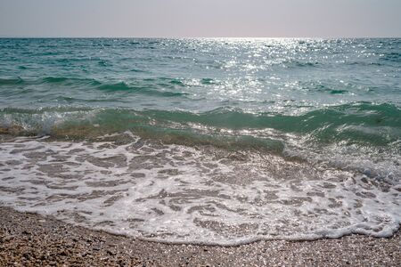 beautiful sea at noon in spring, clear water, rocky beach. silent waves are illuminated by the midday sunの写真素材