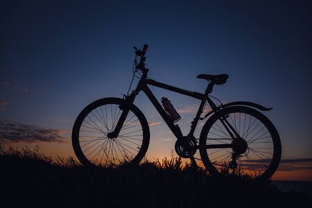 silhouette of a bicycle on the sunset sky. wonderful rural countryside. Weekend in fresh air, among nature.の写真素材