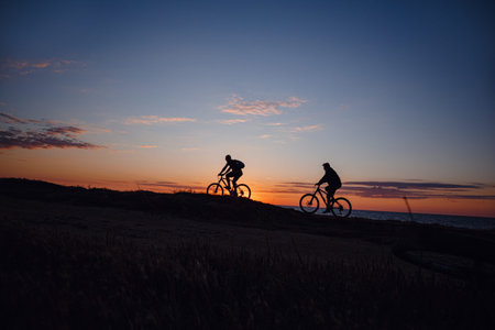two friends on bikes enjoy a beautiful sunset. Idea and concept of physical activity and healthy...
