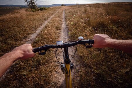 Bike handle bar with lake and sunshine in the background. focus on bike handle bar. picturesque village road at sunsetの写真素材