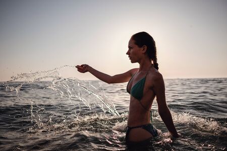 Beautiful emotional Model Girl making splash in the sea and laughing. Beautiful Woman Hot Girl enjoying the Waves of the Ocean. Tropical vacationの写真素材