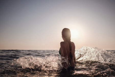 Beautiful emotional Model Girl making splash in the sea and laughing. Beautiful Woman Hot Girl enjoying the Waves of the Ocean. Tropical vacationの写真素材