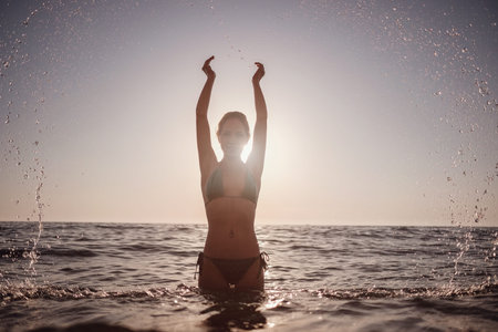 Beautiful emotional Model Girl making splash in the sea and laughing. Beautiful Woman Hot Girl enjoying the Waves of the Ocean. Tropical vacationの写真素材