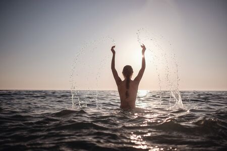 Beautiful emotional Model Girl making splash in the sea and laughing. Beautiful Woman Hot Girl enjoying the Waves of the Ocean. Tropical vacationの写真素材