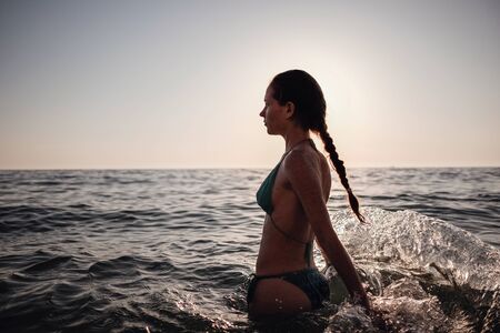 Beautiful emotional Model Girl making splash in the sea and laughing. Beautiful Woman Hot Girl enjoying the Waves of the Ocean. Tropical vacationの写真素材