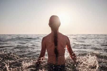 Beautiful emotional Model Girl making splash in the sea and laughing. Beautiful Woman Hot Girl enjoying the Waves of the Ocean. Tropical vacationの写真素材