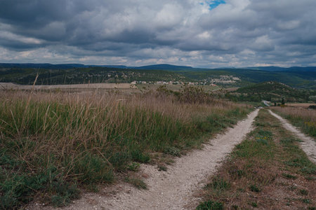 empty dirt road on top of a hill, dramatic sky. idea and concept of travel, open borders and freedomの写真素材
