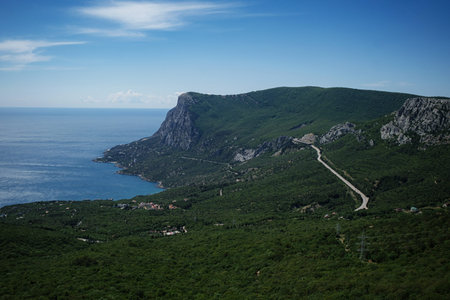The picturesque landscape of mountains covered by dense green forest with the sea in the background....