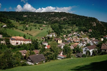 Summer view of a beautiful apline village in Switzerland. green field, footpath with wooden fence in Switzerland village.の写真素材