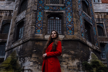 tourist woman visit ancient Istanbul Topkapi palace. Beautiful young woman in a red coat looks at...