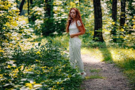 ginger charming woman young beautiful forest green. Caucasian girl relaxing and enjoying life on nature outdoors.の写真素材