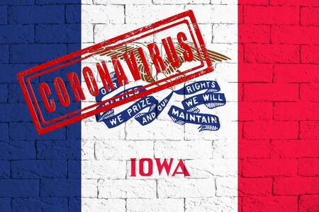 Flag of the State of Iowa painted on grungy brick wall background. with stamp CORONAVIRUS, idea and concept of healthcare, epidemic and disease in USAの写真素材