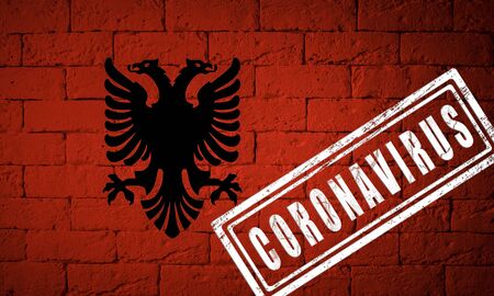 Flag of the Albania with original proportions. stamped of Coronavirus. brick wall texture. Corona virus concept. On the verge of a COVID-19 or 2019-nCoV Pandemic.の写真素材