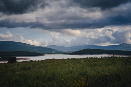 A lake in the valley among the mountains before it rains. Beautiful sunset light. Mountain valley...