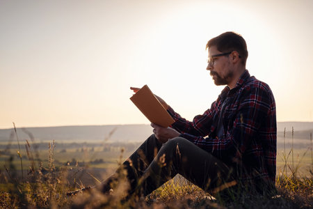 man travel relax in the holiday. seats relax read books on rocky cliffs. Silhouette of man reading...