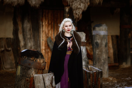 Beautiful blonde Viking dressed in a black cloak against the backdrop of the castle. beautiful film...