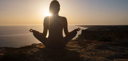 Young woman practicing yoga over sunset sea. meditation in the lotus position. Yoga silhouette....
