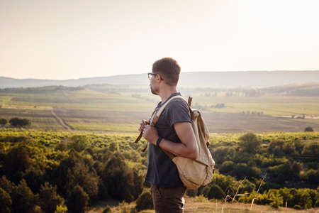 A man standing on a mountain as the sun sets. Enjoying nature sunset. Relaxing in mountains at sunrise. Trekking conceptの写真素材