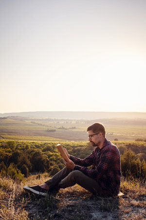 man travel relax in the holiday. seats relax read books on rocky cliffs. Silhouette of man reading...