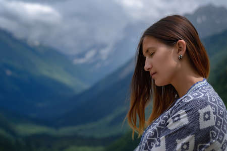 Stylish female hipster walking on top of mountains. Happy young woman exploring sunny mountains. Travel and wanderlust concept. Amazing atmospheric moment. North Caucasus, Dombai, Russia.の写真素材