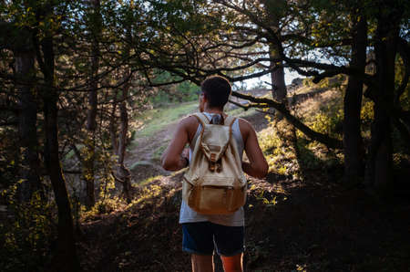 Man Traveler with backpack hiking outdoor in summer sunset forest. Travel Lifestyle and Adventure concept.の写真素材