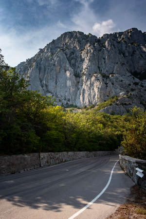 asphalted road in the mountains, beautiful sunshine, summer vacation time. Vintage toning. Travel background. Highway in european mountainsの写真素材